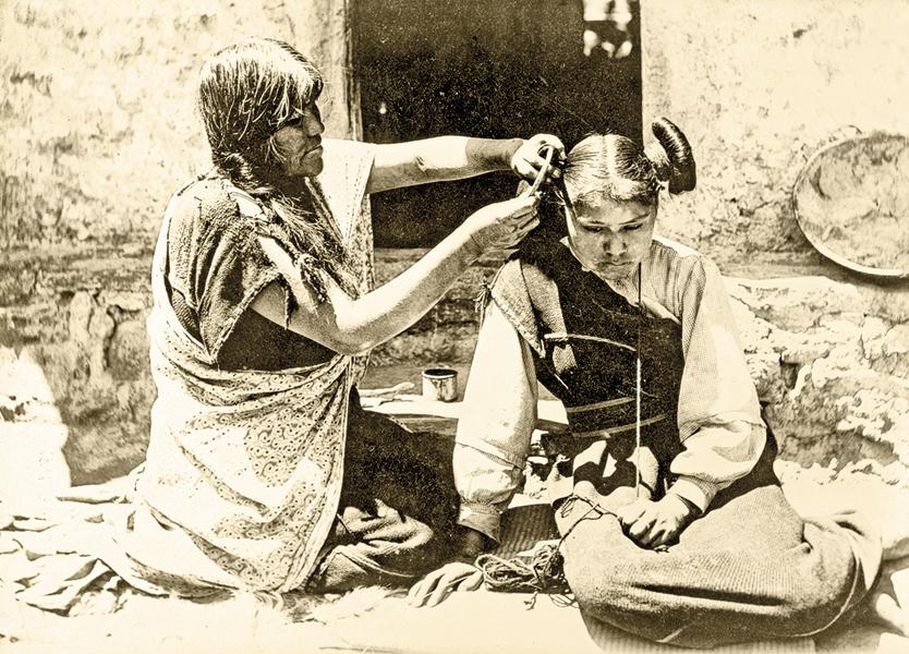 Hopi HairdresserIn northeastern Arizona, this kneeling Hopi woman combed and arranged the maiden’s hair into whorls, a coiffure that represented the squash flower and symbolized that a girl was of marriageable age.– Courtesy Library of Congress –>/i>