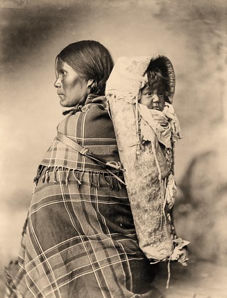 Peearat and BabyThe Utes traditionally made cradleboards out of willow, but the reservation period began a trend of inserting boards into buckskin sacks, like the cradleboard holding Peearat’s baby in this 1899 photograph.– Courtesy Library of Congress –