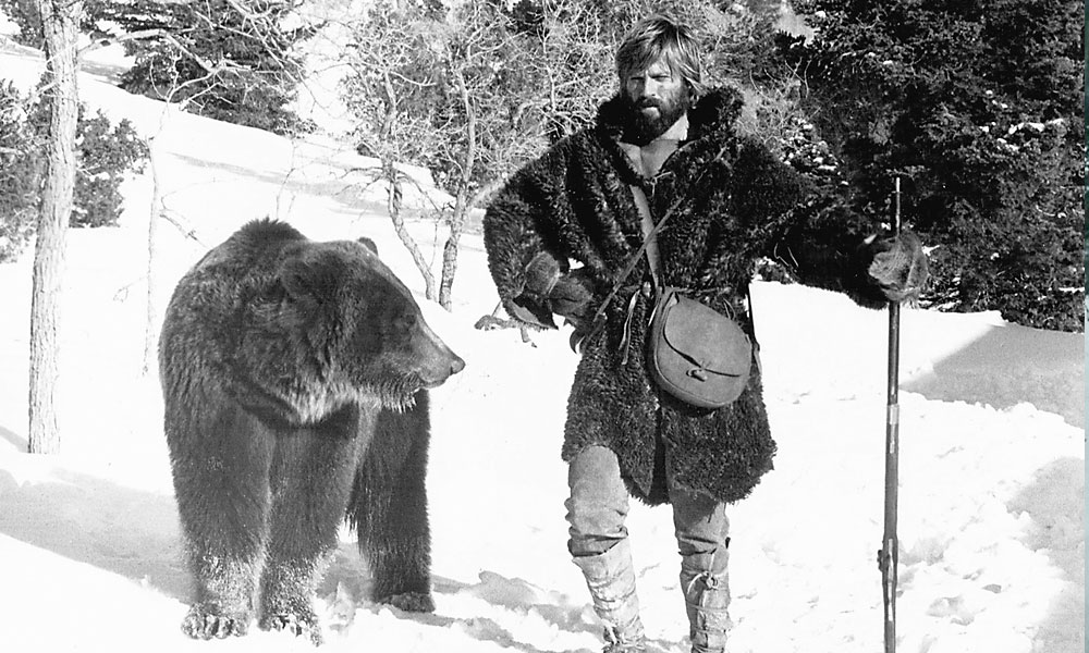 Fraser Heston voted 1972’s Jeremiah Johnson the best mountain man movie. Dan Haggerty concurs: “Robert Redford did such a great job on it; no one could have done it better.” In the film, Redford’s character (above) learns the basics of mountain survival from an older mountain man who specializes in hunting grizzly bears. – Courtesy Warner Bros. –