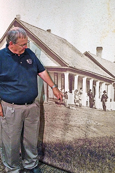 Interpreter Paul Nelson, who walks visitors through the fort’s history, points to a photo of the original officer’s quarters.