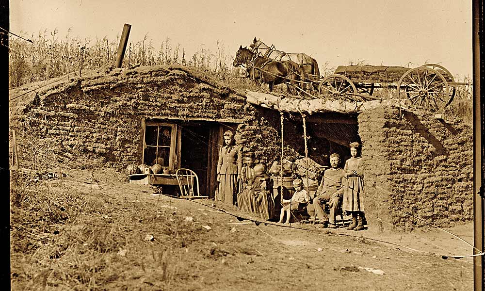 Emigrants to the treeless plains of Nebraska had to build their first homes from blocks of sod cut from the prairie. In 1892, a family posed for traveling photographer Solomon D. Butcher next to their humble abode on the South Loup River, near Virge Allen Homestead in Custer County. – Solomon D. Butcher/ Library of Congress –