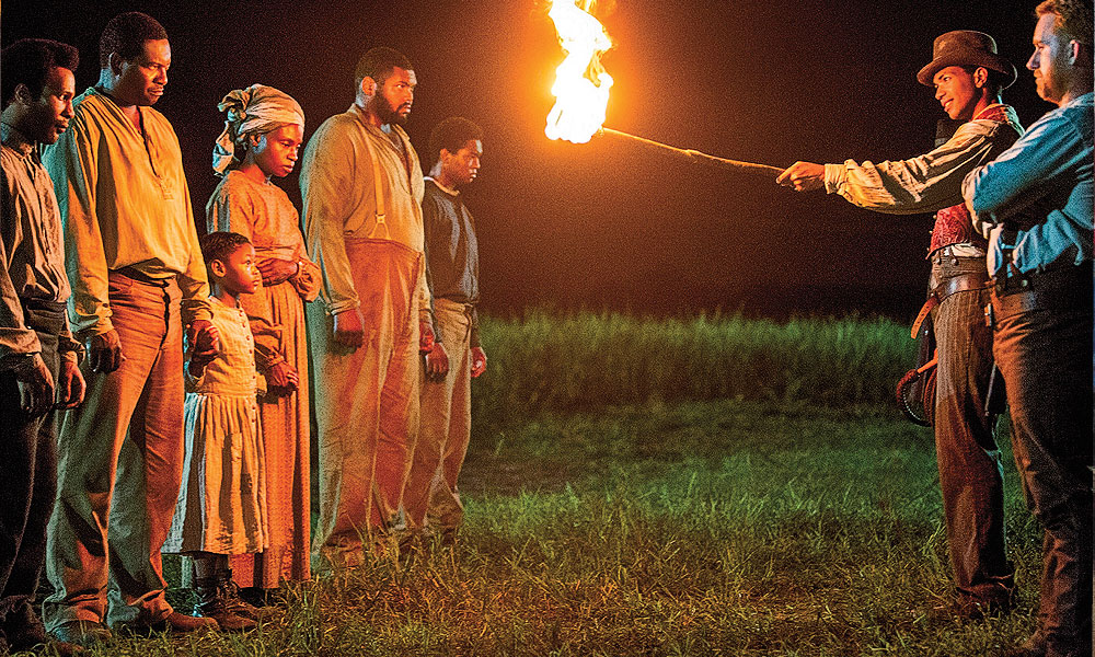 Hard to tell which side Cato (Alano Miller) is on when he menaces some of the other Macon 7 slaves with a fire torch in Season One of the excellent Underground series. His cautionary tale against escaping, however, has a surprising twist for his two white overseers. Season Two, premiering on March 8, follows the Macon 7 heroes on their harrowing journey to freedom. – All Underground photos courtesy WGN America –